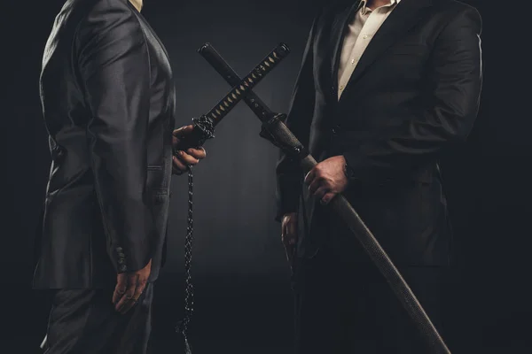 Cropped shot of meeting of modern samurai in suits with katana swords isolated on black — Stock Photo