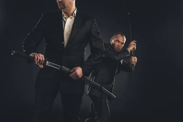 Two mature modern samurai with katanas isolated on black — Stock Photo