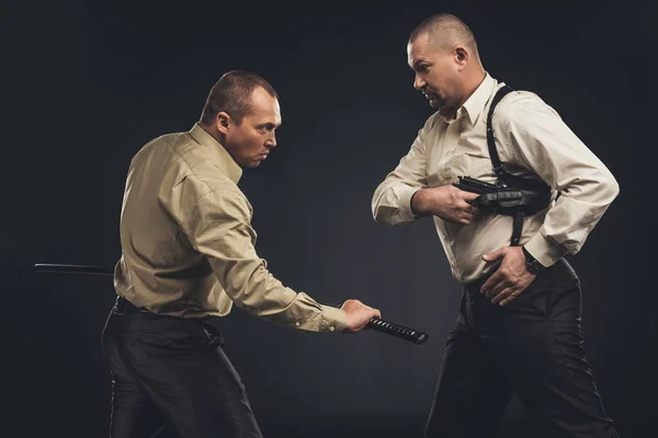 Vista lateral de hombres luchando con arma y espada katana sobre negro - foto de stock