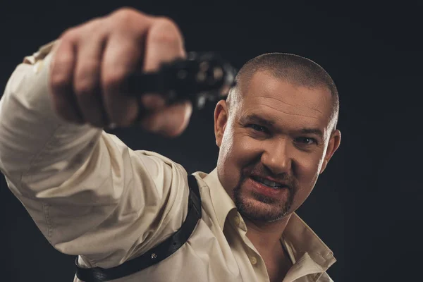 Dangerous angry man aiming gun at camera isolated on black — Stock Photo