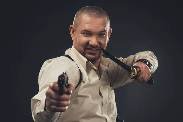 Dangereux homme souriant avec couteau et pistolet regardant la caméra — Photo de stock