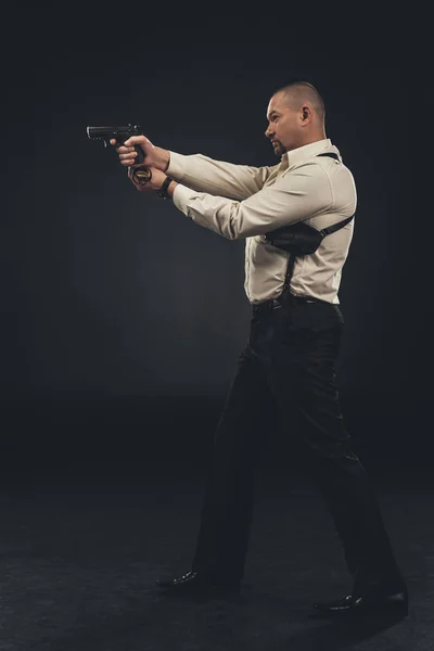 Side view of security man holding gun on black — Stock Photo