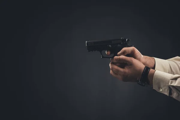 Cropped shot of man holding gun isolated on black — Stock Photo