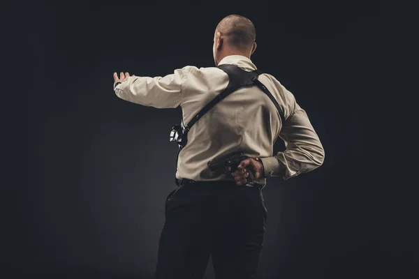 Security man showing stop sign and holding gun behind back — Stock Photo