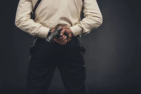 Visão traseira de homem de camisa segurando arma atrás das costas — Fotografia de Stock