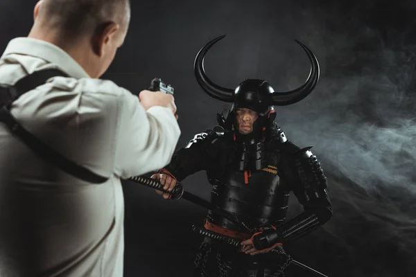 Mann zielt mit Waffe auf gepanzerte Samurai — Stockfoto