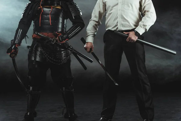 Schnappschuss von modernem Mann und Samurai mit Katana-Schwertern auf Schwarz — Stockfoto