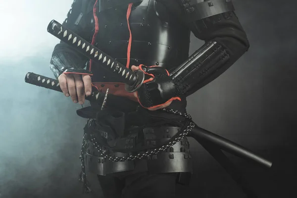 Recortado disparo de samurai en armadura con espadas sobre fondo oscuro con humo - foto de stock