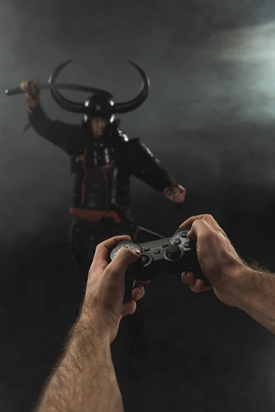 Cropped shot of man controlling samurai character with gamepad on black — Stock Photo