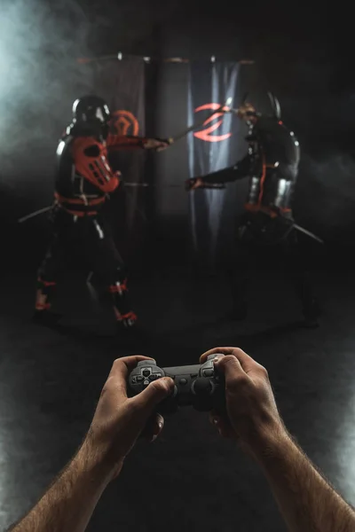 Recortado tiro de jugar samurai lucha con gamepad en la vida real - foto de stock