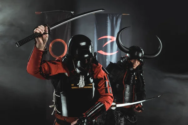 Armored samurai fighting with katana swords in front of clan symbols on flags — Stock Photo