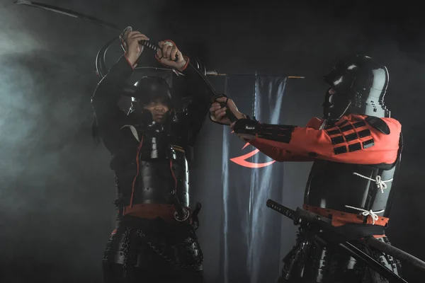 Samurais blindados lutando com espadas na frente de símbolos do clã em bandeiras — Fotografia de Stock