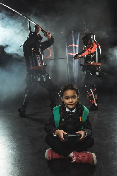 Petit écolier jouer samouraï combats avec gamepad dans la vraie vie — Photo de stock