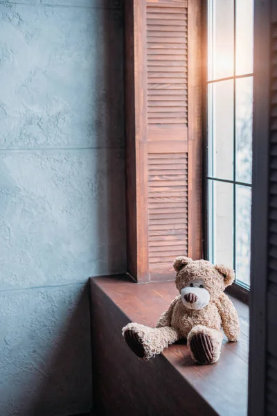 Osito de peluche en el alféizar de la ventana de la habitación elegante en estilo loft - foto de stock