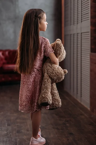 Adorable niño pequeño sosteniendo oso de peluche en loft apartamentos - foto de stock