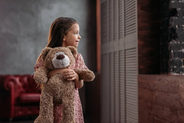 Beautiful little child holding teddy bear at home — Stock Photo