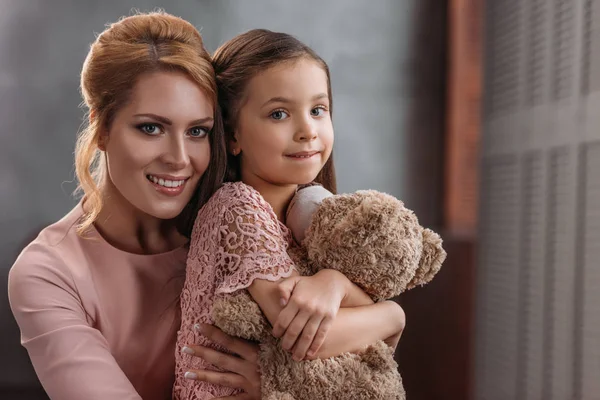 Mutter umarmt ihre Tochter, während sie Teddybär hält — Stockfoto