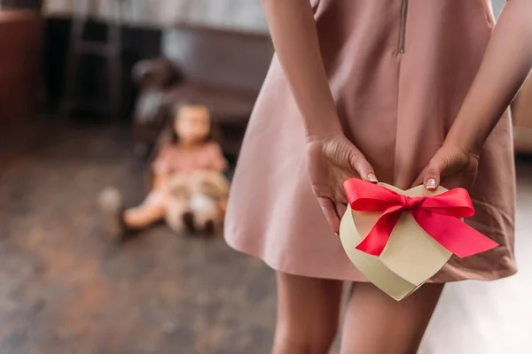 Tiro cortado de mãe escondendo presente de aniversário para a filha nas costas — Fotografia de Stock