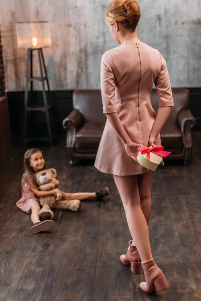 Madre ocultando regalo de cumpleaños para la hija detrás de la espalda - foto de stock