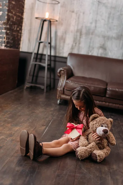 Kleines Kind hält Geschenkbox in Herzform auf dem Boden — Stockfoto