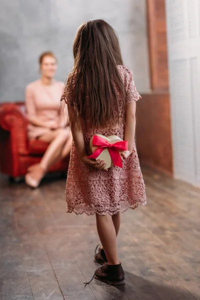 Hija ocultar regalo para la madre en madres día detrás de la espalda — Stock Photo