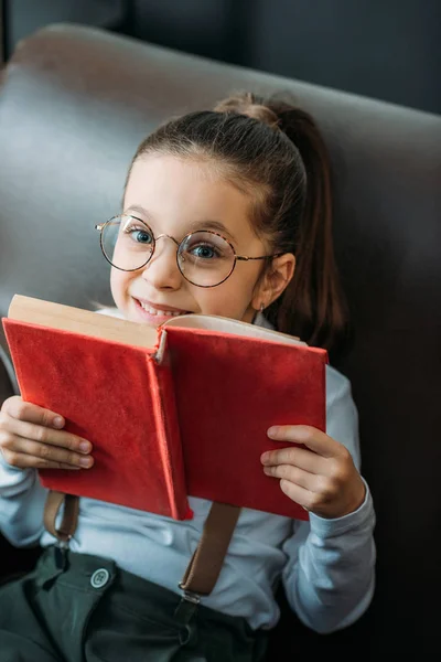 Primer plano retrato de niño feliz con libro en el sofá - foto de stock