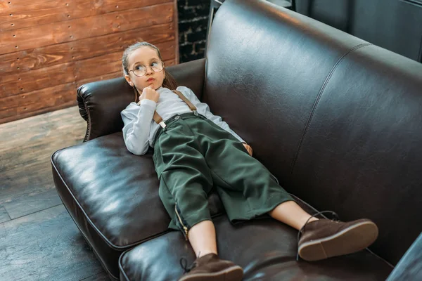 Adorable little child in stylish clothing relaxing on couch at home — Stock Photo