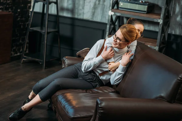 Tochter umarmt ihre Mutter von hinten auf Couch zu Hause — Stockfoto