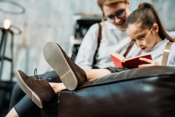 Primer plano de la madre y la hija leyendo libro juntos en el sofá — Stock Photo