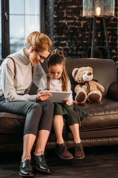 Mother and daughter using tablet together on couch — Stock Photo