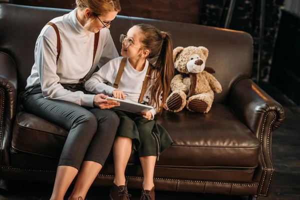 Glückliche junge Mutter und Tochter mit Tablet zusammen auf der Couch — Stockfoto