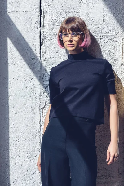 Menina elegante com cabelo rosa inclinado na parede e olhando para longe — Fotografia de Stock