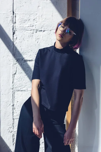 Chica elegante apoyado en la pared y de pie en la sombra - foto de stock