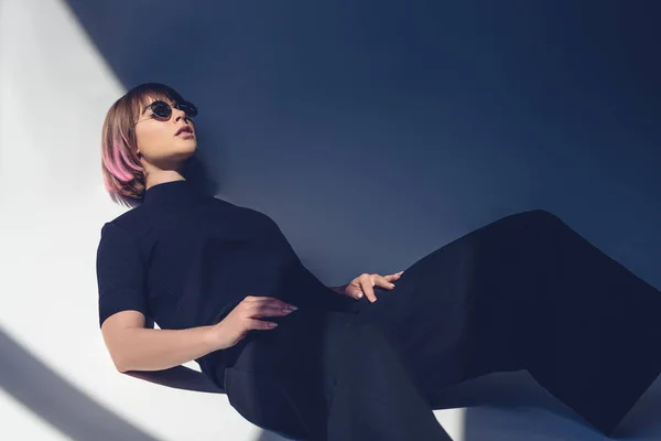 Menina elegante deitado em roupas pretas e óculos de sol — Fotografia de Stock