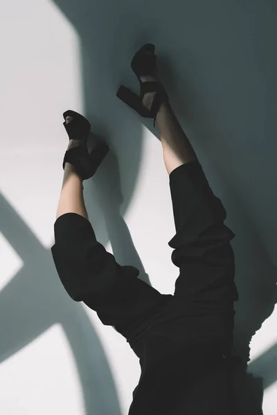 Cropped image of fashionable girl lying in black clothes on white — Stock Photo