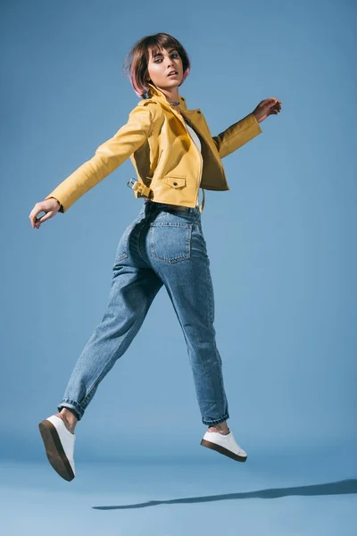 Élégant fille sautant et regardant caméra sur bleu — Photo de stock