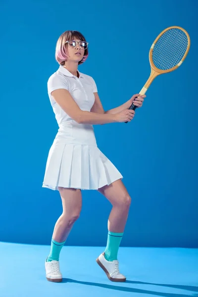 Теннисистка, стоящая в позе с теннисной ракеткой на синей — стоковое фото