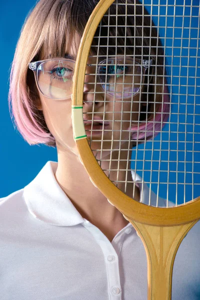 Портрет теннисиста, покрывающий половину лица теннисной ракеткой, изолированной на голубом — стоковое фото