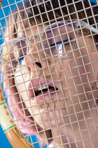 Portrait through tennis racket of sexy woman with closed eyes and open mouth — Stock Photo