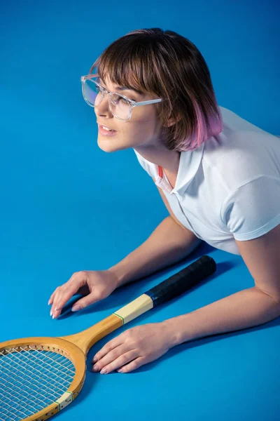 Female tennis player lying with tennis racket on blue — Stock Photo