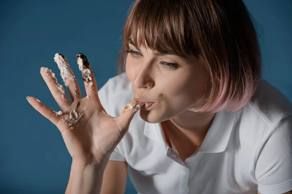 Chica lamiendo dedo con resto de pastel aislado en gris - foto de stock