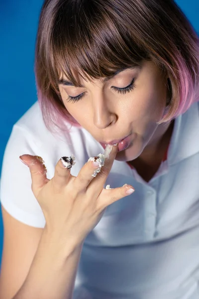Sexy fille lécher doigt avec reste de tarte avec les yeux fermés isolé sur bleu — Photo de stock
