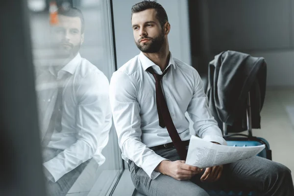 Bel giovane uomo d'affari con giornale in attesa di volo presso la hall dell'aeroporto — Foto stock