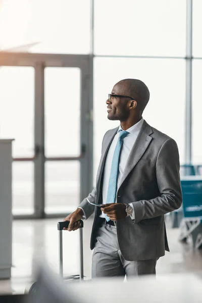 Bell'uomo d'affari con valigia passeggiando vicino alla hall dell'aeroporto — Foto stock