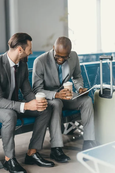 Business colleagues waiting for flight in airport lobby and using tablet — Stock Photo