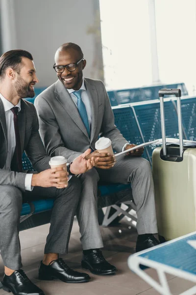 Collègues d'affaires en attente d'un vol dans le hall de l'aéroport avec café à emporter — Photo de stock