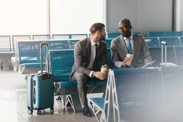 Colegas de negocios esperando el vuelo en el vestíbulo del aeropuerto - foto de stock