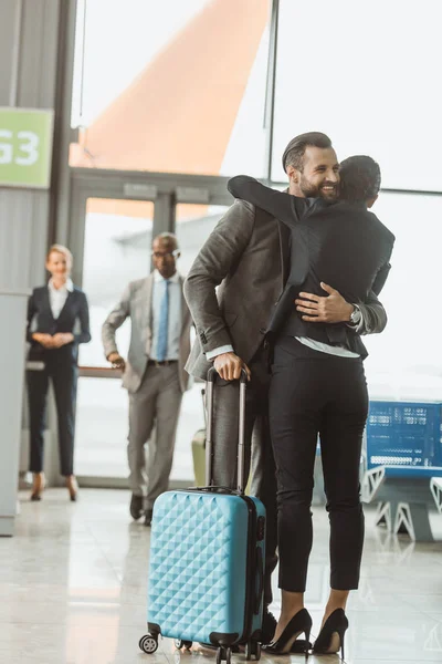 Heureux jeune homme d'affaires embrassant avec femme à l'aéroport — Photo de stock