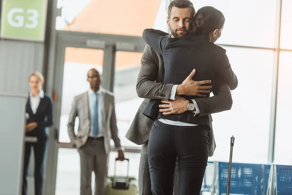 Homem abraçando mulher no aeroporto após longa separação — Fotografia de Stock