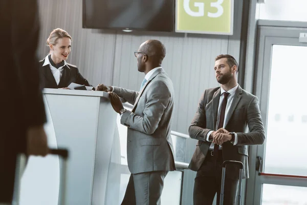 Cola de hombres de negocios en la recepción del aeropuerto para comprar entradas - foto de stock